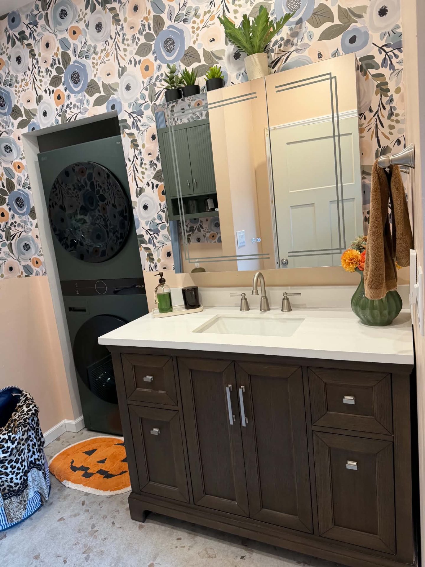 Remodeled bathroom vanity with floral wallpaper and dark wood cabinetry