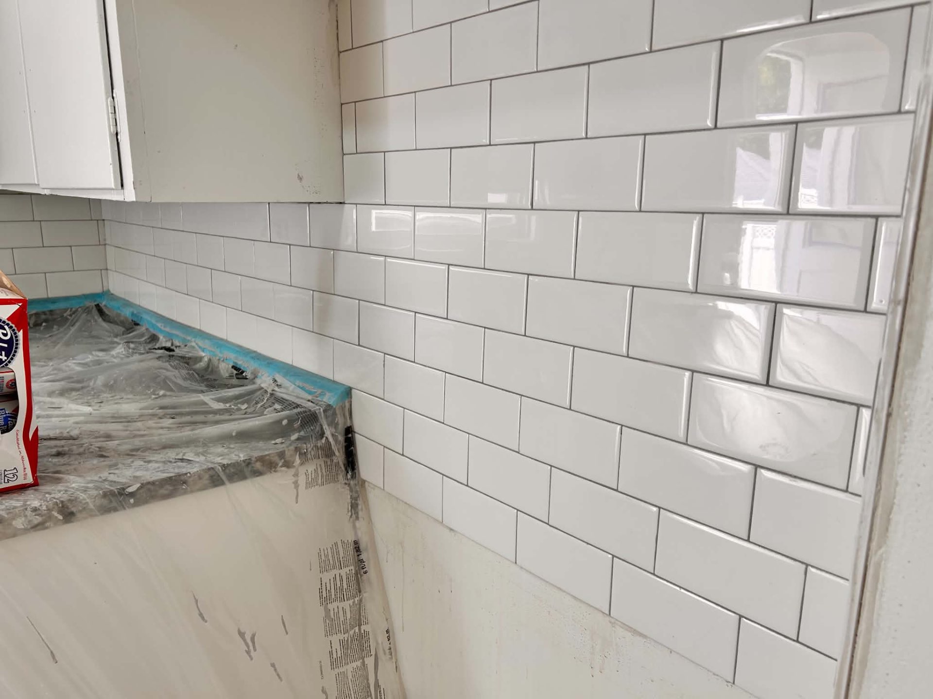Newly installed white subway tile kitchen backsplash